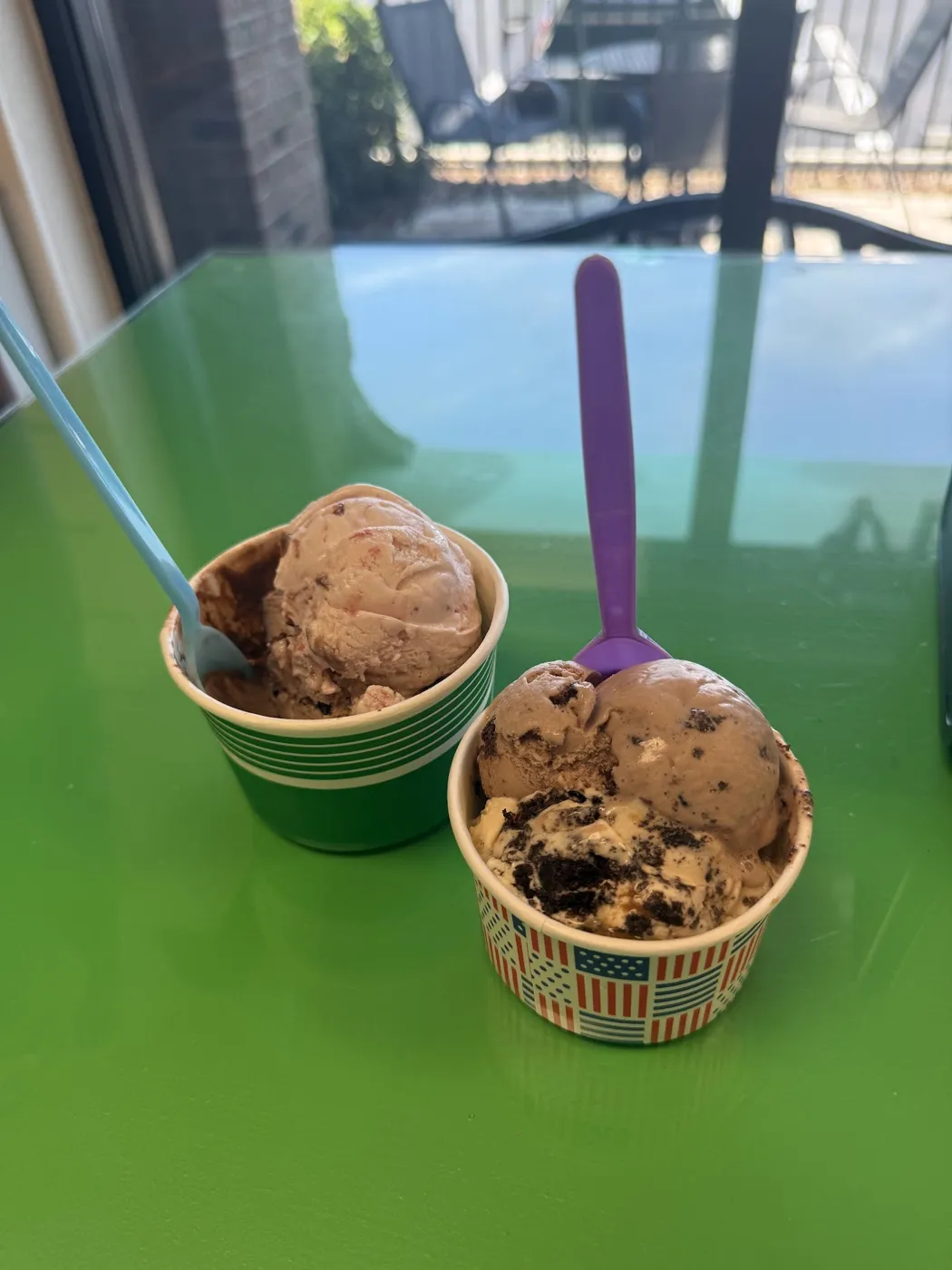 Two cups of ice cream on a green table